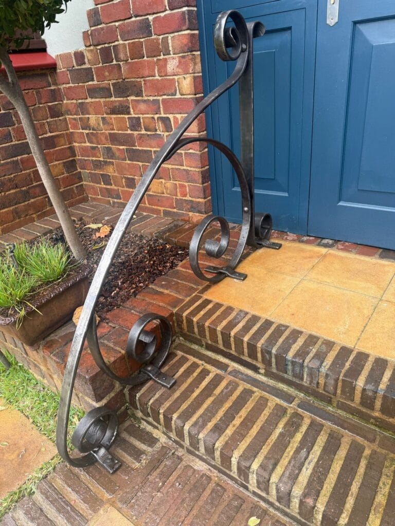 Custom organic curved hand-forged steel stair railing commission by Solms Forge.